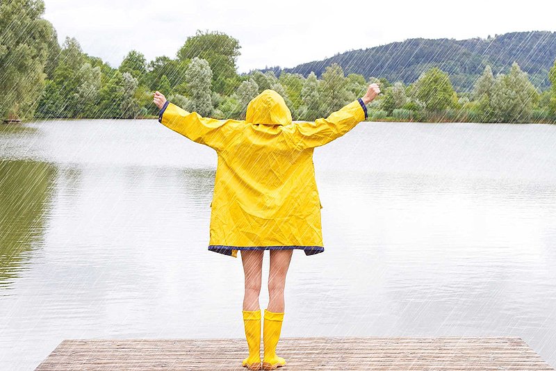 Rohrhof-Apotheke | Allgemeine Stärkung des Immunsystems Ein Kind im Friesennerz und gelben Gummistiefeln steht an einem See auf einem Steg und streckt die Arme in den Sommerschauer